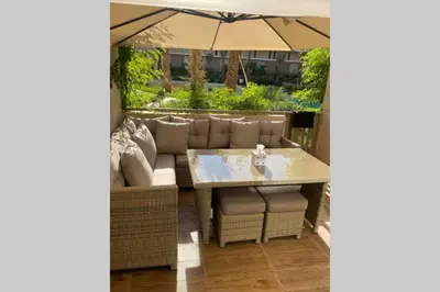 a table and chairs under an umbrella on a patio at Cosy Duplex, dans résidence avec piscine in Marrakech