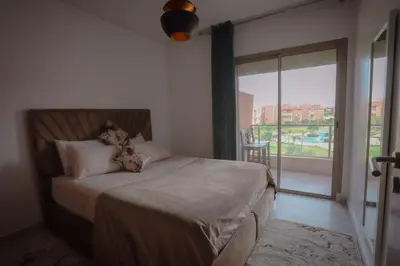 a bedroom with a bed and a large window at Prestigia Golf City Marrakech in Marrakech