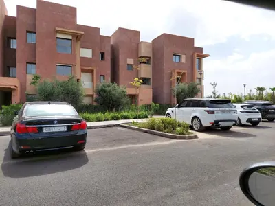 two cars parked in a parking lot in front of a building at Prestigia Golf City Marrakech in Marrakech
