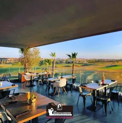 a restaurant with tables and chairs and a view of a golf course at Prestigia Golf City Marrakech in Marrakech