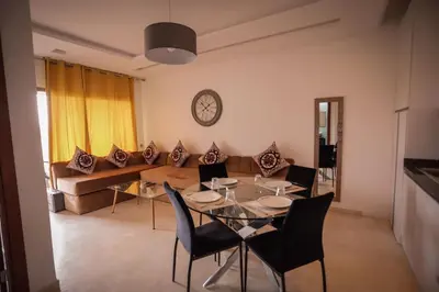 a living room with a table and chairs and a couch at Prestigia Golf City Marrakech in Marrakech