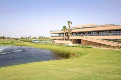a building next to a pond in front of a building at Cosy Loft Emeraude Marrakech Prestigia Golf City in Marrakech