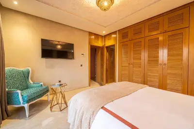 a bedroom with a bed and a chair and a television at Villa Dar Laila in Marrakech