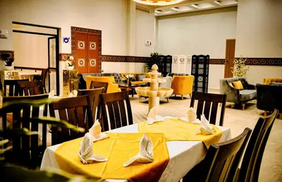 a restaurant with two tables with yellow table cloth at EL MOUSSAFIR HOTEL in Marrakech