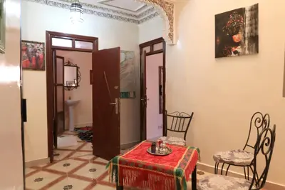 a living room with a table and chairs and a painting at Riad el Boukhiri in Marrakech
