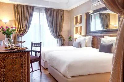 a hotel room with two beds and a desk and a mirror at dar al walidine in Marrakech
