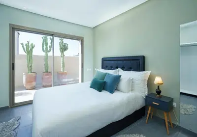 a bedroom with a white bed and a window with cactus at dar al walidine in Marrakech
