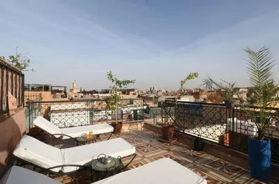 a balcony with white chairs and a view of a city at Riad Maissoun in Marrakech