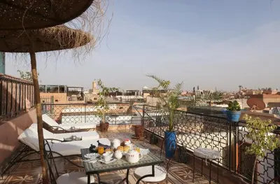 a balcony with tables and chairs and a view of a city at Riad Maissoun in Marrakech