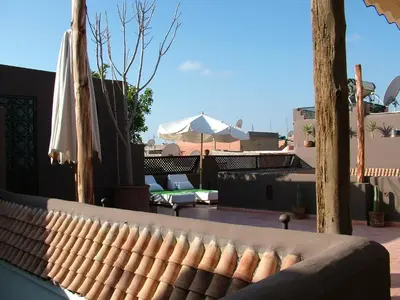 a couch sitting on a balcony with an umbrella at Riad Timila in Marrakech