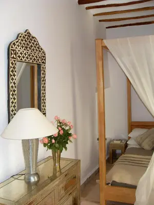 a bedroom with a table with a lamp and a mirror at Riad Timila in Marrakech