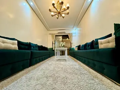 a living room with green couches and a chandelier at Duplex Sabah Opera - Quartier Hivernage in Marrakech