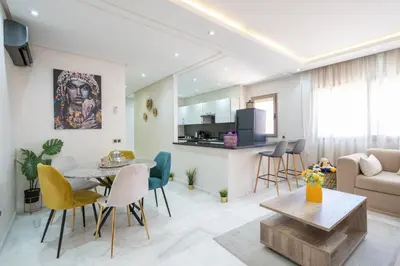 a living room and kitchen with a table and chairs at LUXURY APARTMENT IN THE HEART OF MARRAKECH GUELIZ in Marrakech