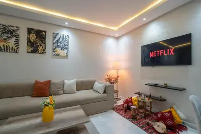 a living room with a couch and a television on the wall at LUXURY APARTMENT IN THE HEART OF MARRAKECH GUELIZ in Marrakech