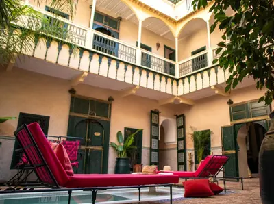 a patio with red chairs and a balcony at Riad Dar Habiba by Garden Wonders in Marrakech