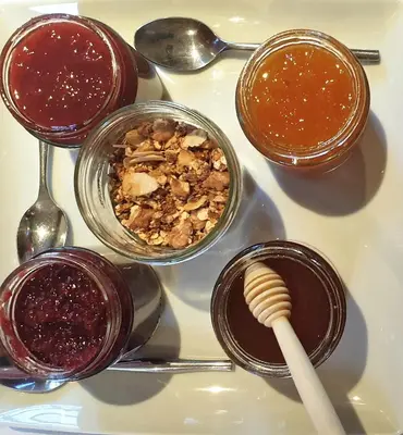 a white table topped with containers of jam and a spoon at Riad l'Escale de Marrakech in Marrakech