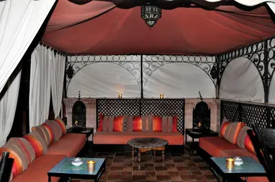 a living room with a red couch and tables at Riad l'Escale de Marrakech in Marrakech