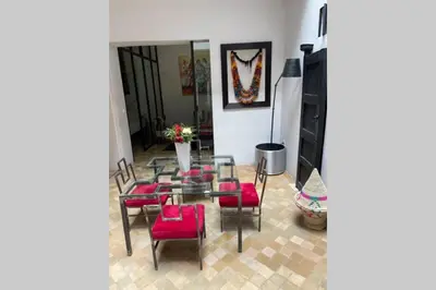 a dining room with a glass table and red chairs at Riad Touareg in Marrakech
