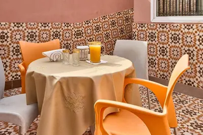 a table with orange chairs and a table with drinks on it at Riad AMBER ZAHRA in Marrakech