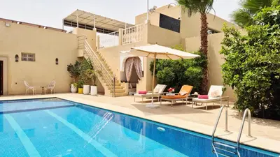 a pool with chairs and an umbrella next to a house at Le clos des oliviers de Marrakech in Marrakech