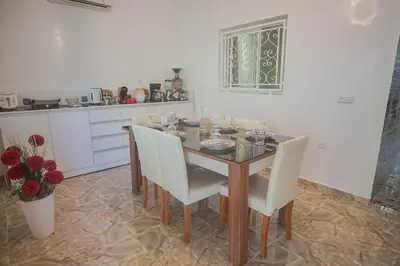 a dining room with a table and white chairs at Le clos des oliviers de Marrakech in Marrakech