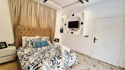 a bedroom with a bed and a tv on the wall at Le clos des oliviers de Marrakech in Marrakech