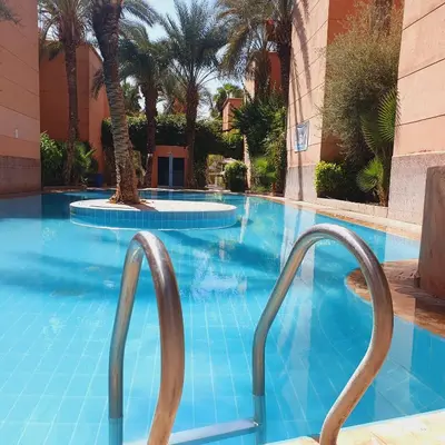 an empty swimming pool with two metal stairs in a hotel at Chez Jasmeene in Marrakech