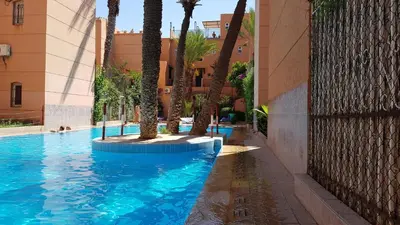 a swimming pool with palm trees next to a building at Chez Jasmeene in Marrakech