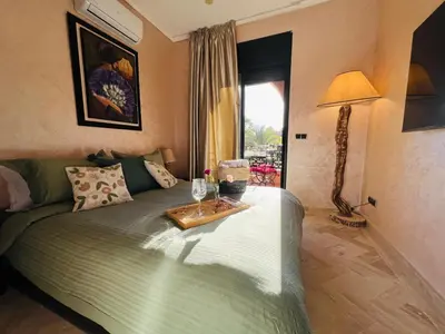 a bedroom with a bed with a table and a lamp at Duplex Atlas Golf Resort Pοοl νieω Seriniτყ & Cαlm in Marrakech