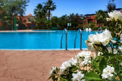 a swimming pool with white flowers in front of it at Duplex Atlas Golf Resort Pοοl νieω Seriniτყ & Cαlm in Marrakech