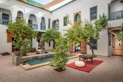 a courtyard with a pool in a building with trees at Riad les remparts de la kasbah in Marrakech