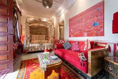 a living room with a red couch and a bed at Riad Hikaya in Marrakech