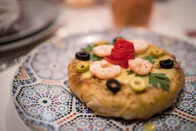 a small pizza with shrimp and a rose on a plate at Riad Hikaya in Marrakech