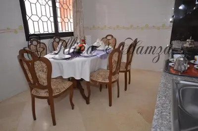 a dining room table with a white table cloth and chairs at Illina & Hamza Apartment in Marrakech
