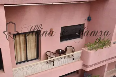 a balcony of a pink building with a tv on it at Illina & Hamza Apartment in Marrakech
