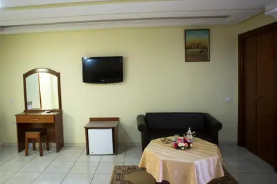 a living room with a table and a tv on the wall at Hotel Gomassine in Marrakech