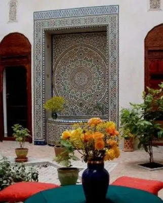 a vase with flowers on a table in front of a wall at Nadir Home in Marrakech