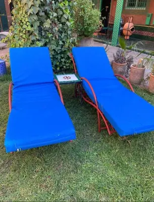 two blue benches sitting in the grass at Charmant Riad avec piscine, au Coeur de Marrakech in Marrakech