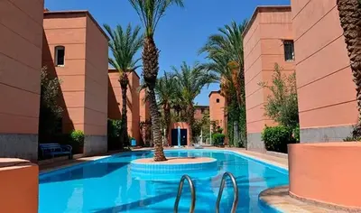a swimming pool with palm trees in a resort at Riad Prestigia in Marrakech