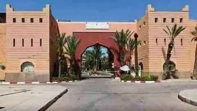 a large brick building with a courtyard with palm trees at Riad Prestigia in Marrakech