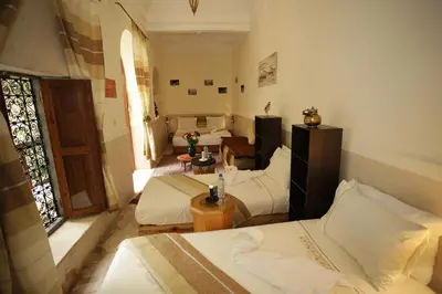 a room with three beds and a table and a window at Riad white flowers in Marrakech