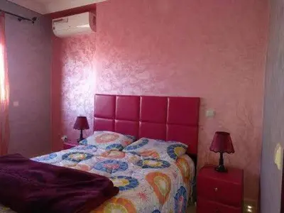 a bedroom with a bed with a pink wall at Superbe appartement avec terrasse in Marrakech