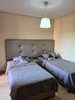 a bedroom with two beds and a light at Appartement chic avec jardin a Prestigia Golf City in Marrakech