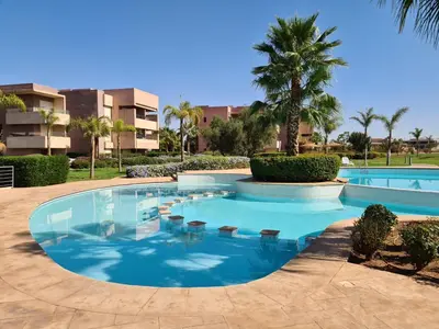 a swimming pool in a resort with palm trees at Appartement chic avec jardin a Prestigia Golf City in Marrakech