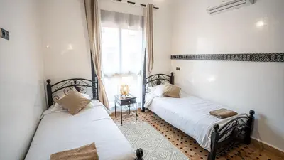 two beds in a room with a window at Appartement aux portes de la palmeraie in Marrakech