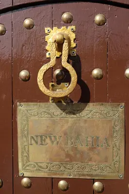 a metal sign on a wooden door with the words new ballilia at New Bahia in Marrakech