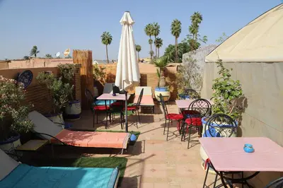 a patio with tables and chairs and a white umbrella at New Bahia in Marrakech