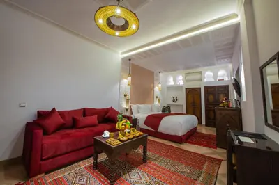 a living room with a red couch and a bed at Riad la clé d'or & spa in Marrakech