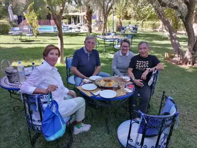 a group of people sitting at a table in the grass at RIAD REDWAN in Marrakech