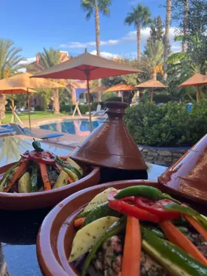 a table with plates of food on a table near a pool at RIAD REDWAN in Marrakech